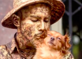 Perrito trabaja con su dueño como estatua callejera